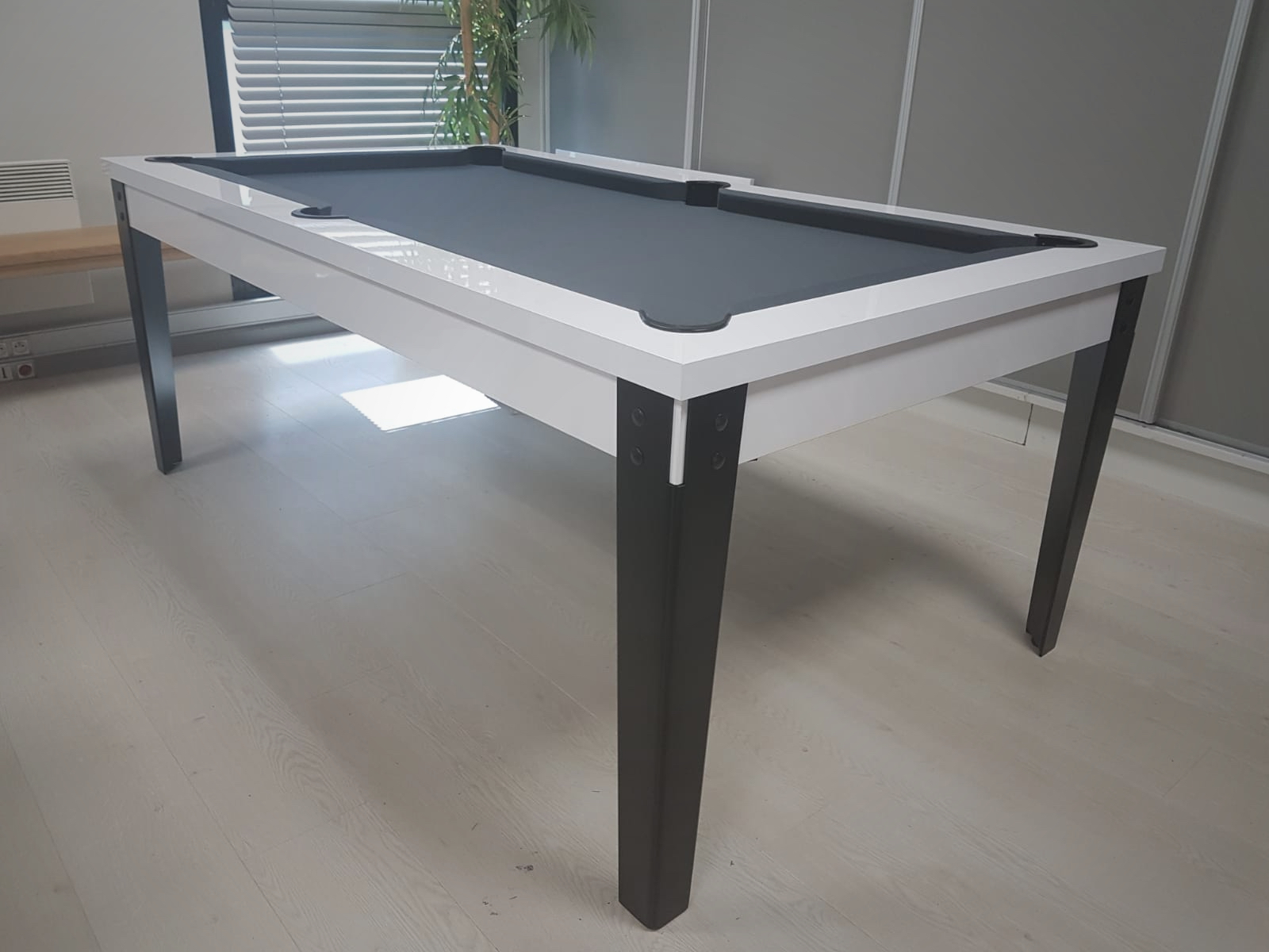 Billard factory blanc brillant avec tissu gris foncé posé sur ses pieds en acier noirs